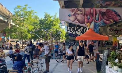 An outdoor farmers market under an elevated expressway.