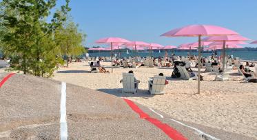 pink umbrellas and a sandy beach next to Lake Ontario