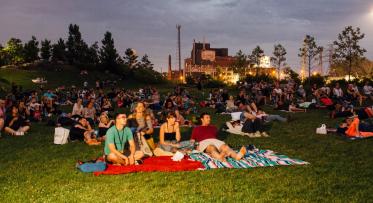 people sitting on the lawn and enjoying a community movie night at Corktown Common