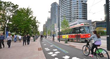 cyclists and pedestrians walking along a new promenade on Queens Quay