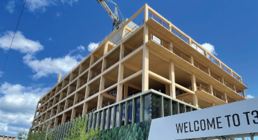 A mass-timber building under construction. Timber frame in foreground and blue sky in background.