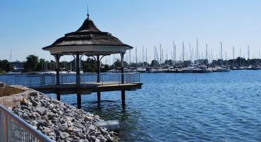 a gazebo on the waterfront with a marina in the background