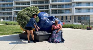 two artists pose in a park with their latest piece of public art