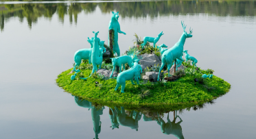 Art installation with model animals all painted blue on a floating island.