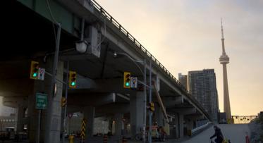 a ramp to an elevated expressway with the CN Tower in the background