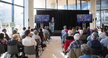 A seated audience facing a person on a podium.