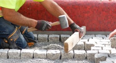 A construction worker laying granite pavers. 