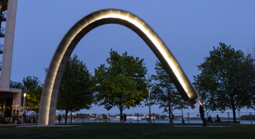 A large public art arch is activated by the artist and lit up at night